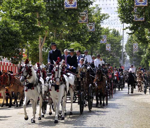 © Jennifer Singleton – Please do not copy or save without permission a long line of horse-drawn carriages parading down the streets of the feria